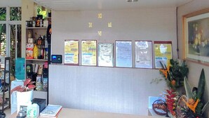 A reception desk with a digital display, framed certificates on the wall, and a variety of items on shelves. - Alejandro'S Suites & Venue (Valencia)