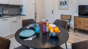 Et moderne køkken med hvide skabe, et spisebord med stole og en loftlampe.
