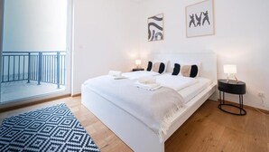 Et moderne soveværelse med en stor seng, en balkon og to billeder hængende på væggen.