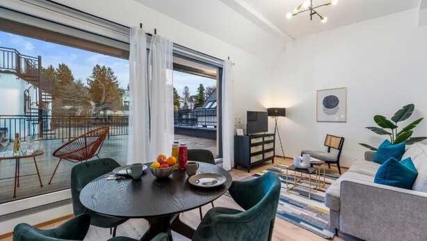 En moderne stue med spiseplads, store vinduer og en balkon.