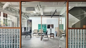 Et moderne kontormiljø med glasvægge, forskellige møbleringer og synlige loftinstallationer.