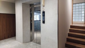Et moderne interiør med en betonvæg, en trætrap og en glasdør til elevator.