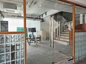 Un espace intérieur comprenant un escalier, une cloison en verre et un fauteuil agrémenté d’un tableau.