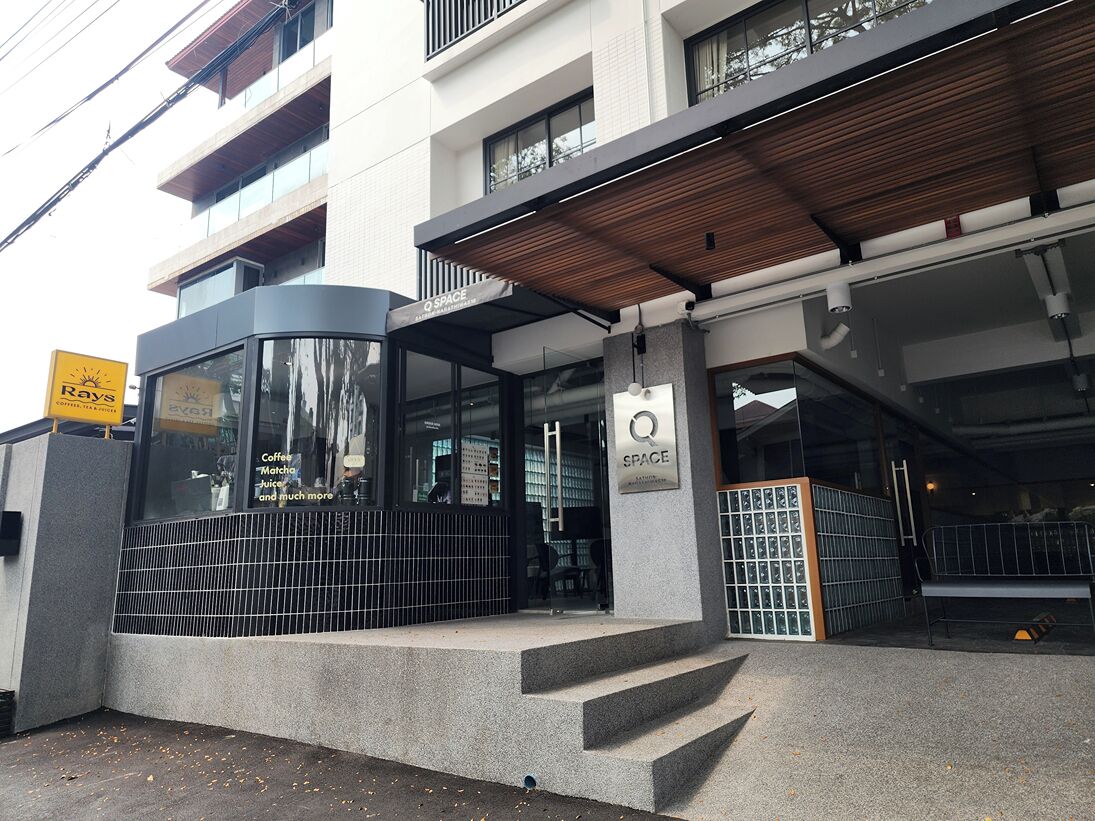 A modern building with a café named 'Q SPACE' featuring a glass entrance and a wooden ceiling.