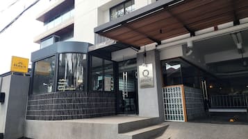 A modern building with a café named 'Q SPACE' featuring a glass entrance and a wooden ceiling.