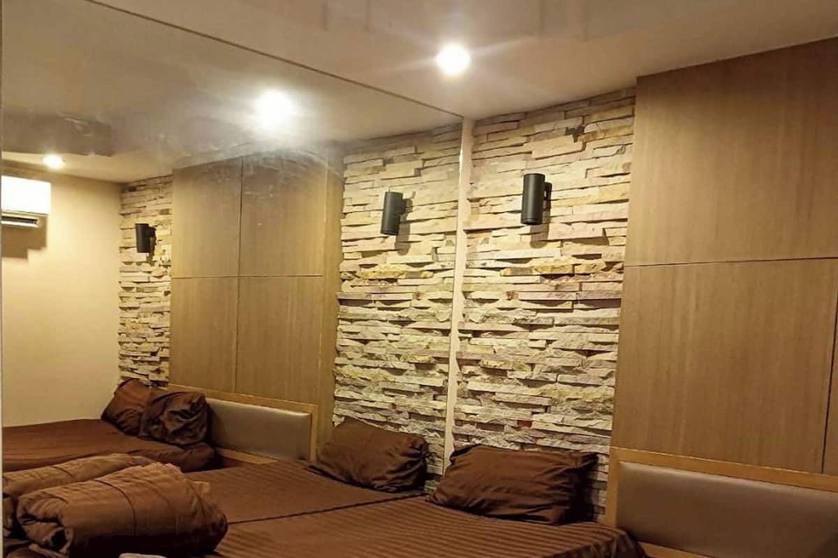 Un dormitorio con una cama grande, una cama más pequeña, una mesita de noche y una lámpara fijada a la pared.