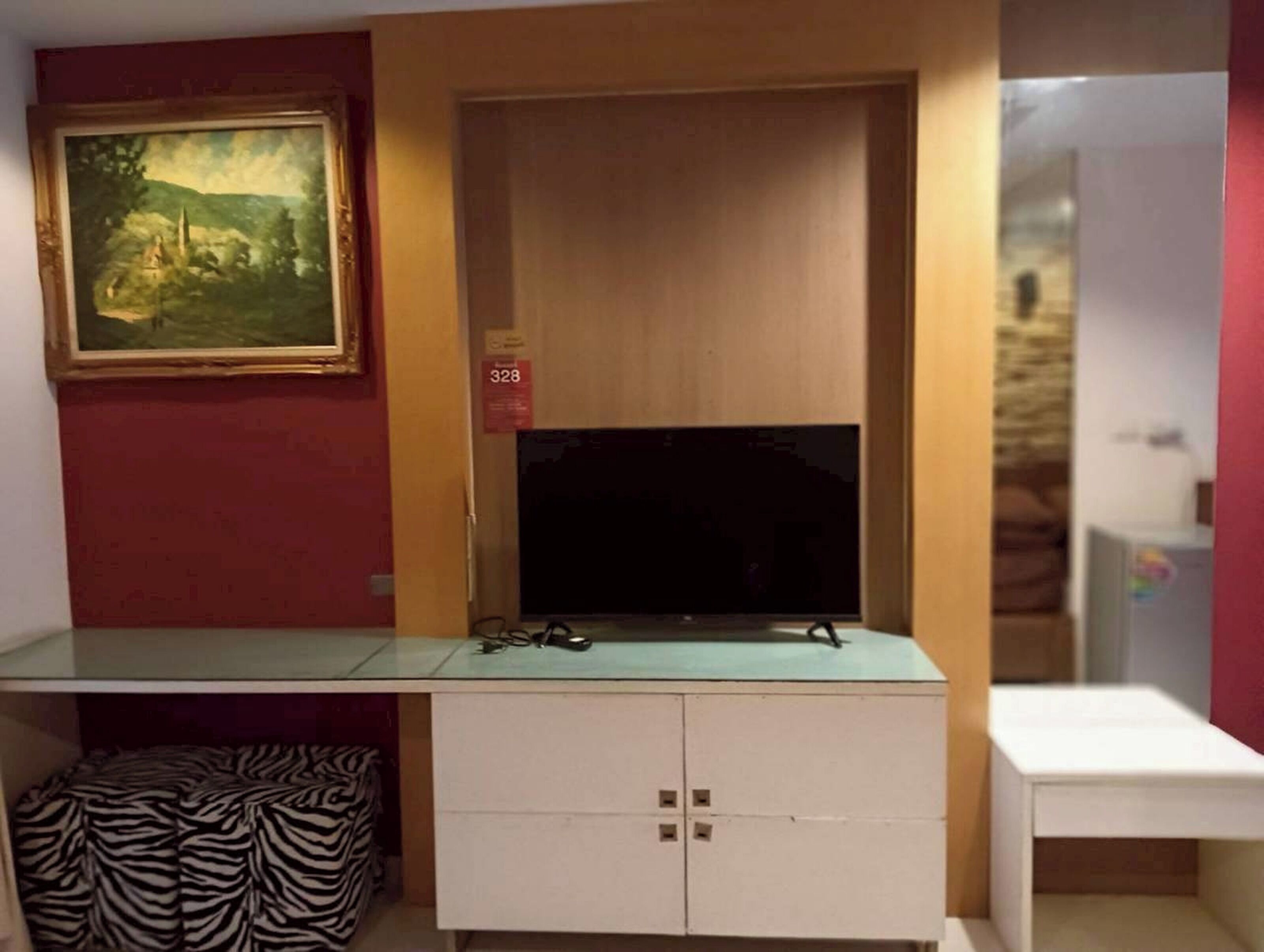 A room with a TV on a cabinet, a zebra-patterned chair, and a painting on the wall.