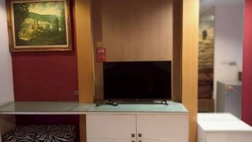A room with a TV on a cabinet, a zebra-patterned chair, and a painting on the wall.