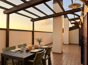 Een eethoek met een houten pergola, een ontbijttafel en uitzicht op de lucht.