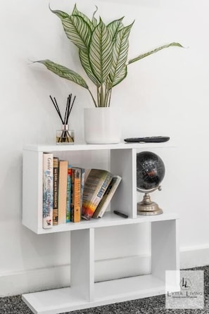 A white bookshelf with books, a globe, and a potted plant.