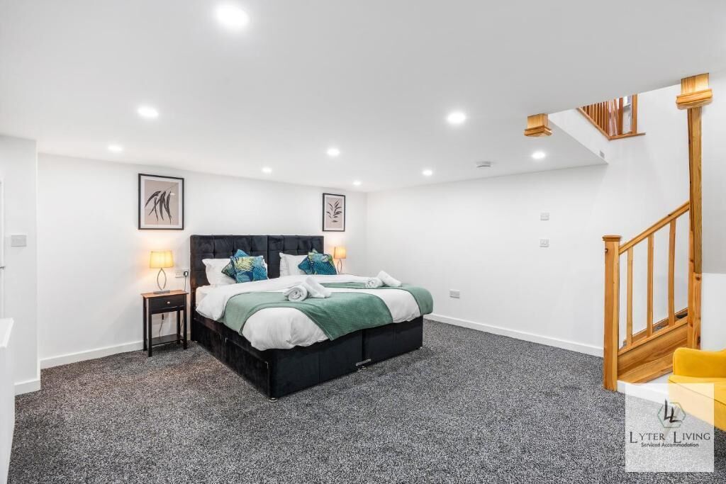Een moderne slaapkamer met een groot bed, een nachtkastje en een trap.