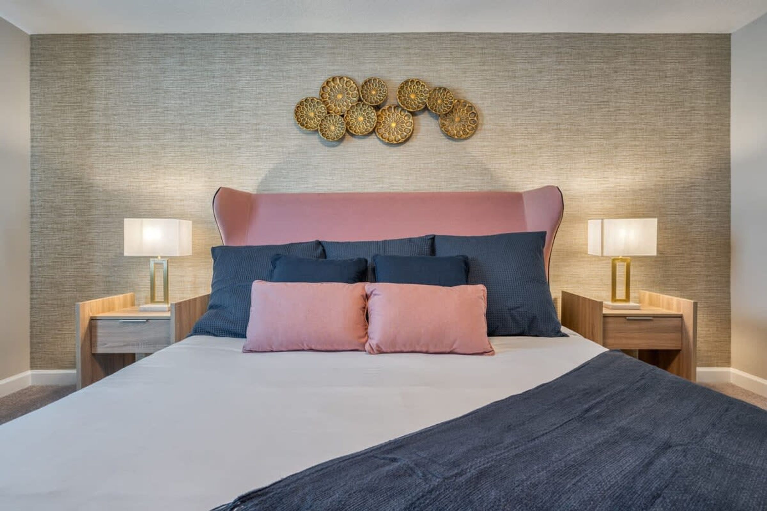 Een verzorgde hotelkamer met een groot bed, twee nachtkastjes en een decoratief kunstwerk boven het bed.