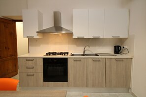 A modern kitchen with a gas stove, oven, and a coffee maker. - Farris Apartment - vacations by the sea (La Caletta)