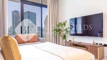 Een moderne hotelkamer met een groot bed, een flatscreen televisie, een houten console en uitzicht op de skyline van de stad.