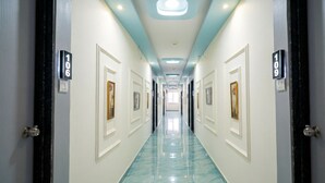 Un couloir d’hôtel avec des portes numérotées 106 et 109, un sol en marbre et un éclairage encastré.