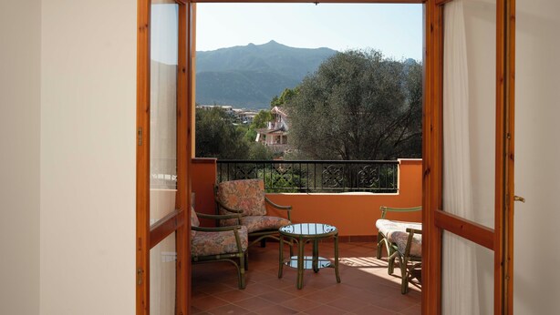 Varanda com vista para montanhas, uma mesa e duas cadeiras.