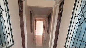 A corridor with tiled flooring and barred windows on both sides. - Flamingo Hotel Bombolulu  (Mombasa)