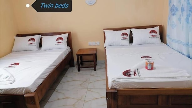 Twin beds with matching pillows, a small wooden nightstand, and a sign indicating 'Twin beds'. - Flamingo Hotel Bombolulu  (Mombasa)