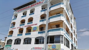 A multi-story building with balconies, a pharmacy, and a hotel named Flamingo Hotel & Accommodation. - Flamingo Hotel Bombolulu  (Mombasa)