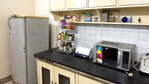 Una cocina con dos refrigeradores, un microondas, un estante para especias y un reloj en la pared.