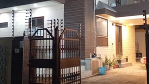 Una casa de dos pisos con entrada protegida por un portón, un balcón y un porche bien iluminado.