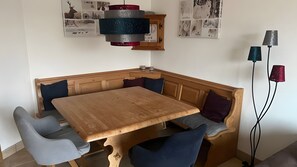 A corner dining area with a wooden table and bench, a wall-mounted clock, and a floor lamp. - Apartment 'Schladming Planai Mitte' with Mountain View, Private Terrace and Wi-Fi (Schladming)