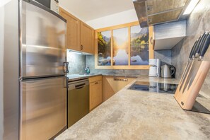 Una cocina moderna con electrodomésticos de acero inoxidable, armarios de madera, encimera de granito y una vista panorámica por la ventana.