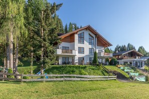 A multi-story building with a sloped roof, surrounded by greenery and trees. - Apartment 'Schladming Planai Mitte' with Mountain View, Private Terrace and Wi-Fi (Schladming)