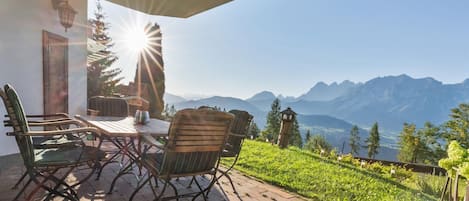 An outdoor patio with a table and chairs, overlooking a mountainous landscape.
