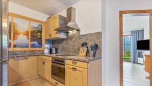 A modern kitchen with wooden cabinets, a stainless steel range, and a large window offering a scenic view. - Apartment 'Schladming Planai Mitte' with Mountain View, Private Terrace and Wi-Fi (Schladming)
