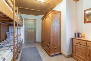 Una habitación con literas, un armario, una puerta y una pequeña estantería.