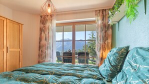 A bedroom with a bed, curtains, a window with a mountain view, and a hanging plant. - Apartment 'Schladming Planai Mitte' with Mountain View, Private Terrace and Wi-Fi (Schladming)