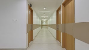 A long, narrow hallway with lockers on both sides and a tiled floor. - Hotel Vivanta Inn (Veraval)