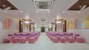 A spacious hall with rows of chairs, ceiling fans, and recessed lighting. - Hotel Vivanta Inn (Veraval)