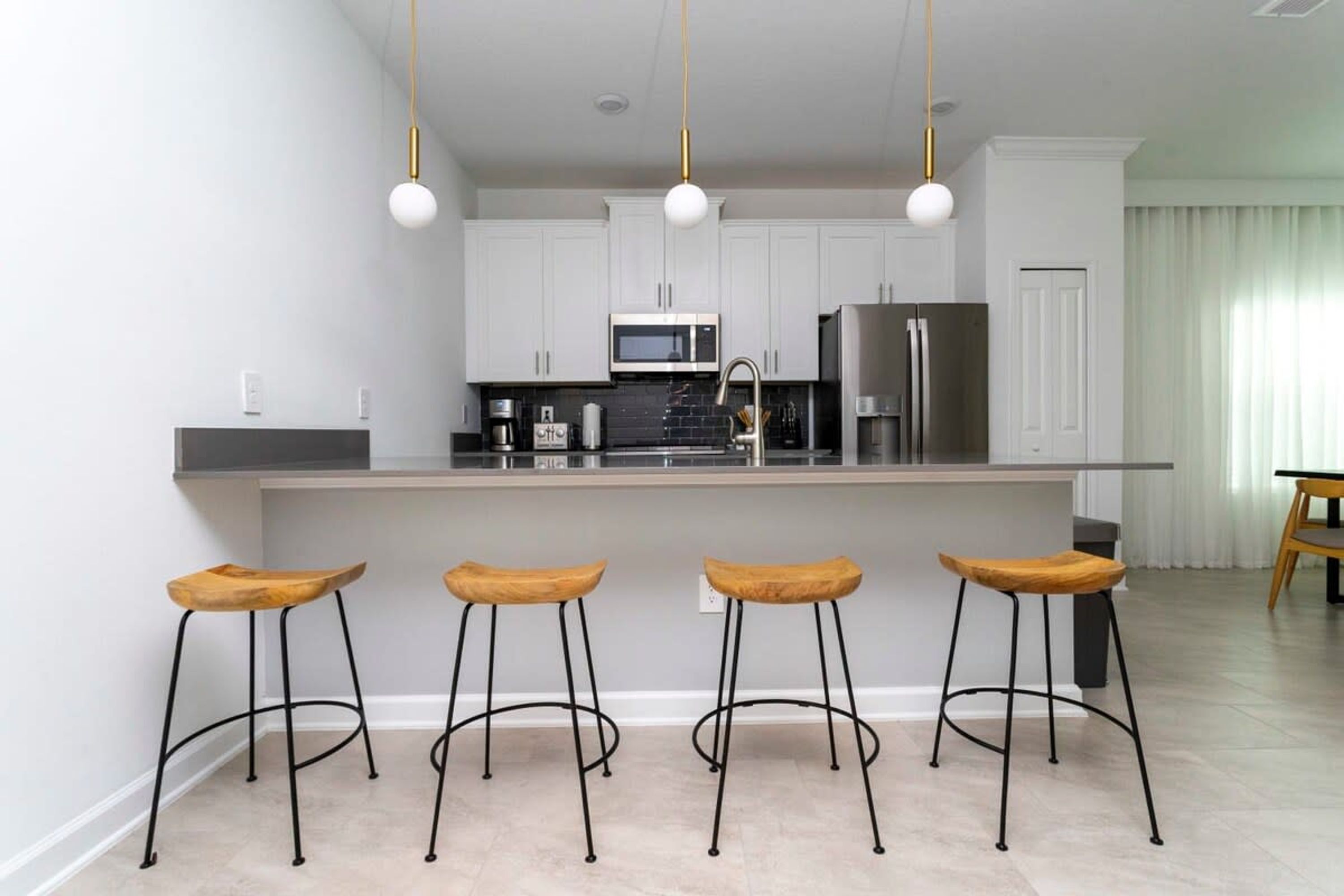 A modern kitchen with white cabinets, stainless steel appliances, and a central island with bar stools.