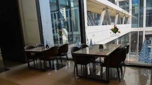 Un'area pranzo moderna con tavolo e sedie in vetro, ampie finestre e vista sulla città.