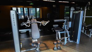 Una palestra con diverse macchine per esercizi, tra cui una panca per pesi e manubri.