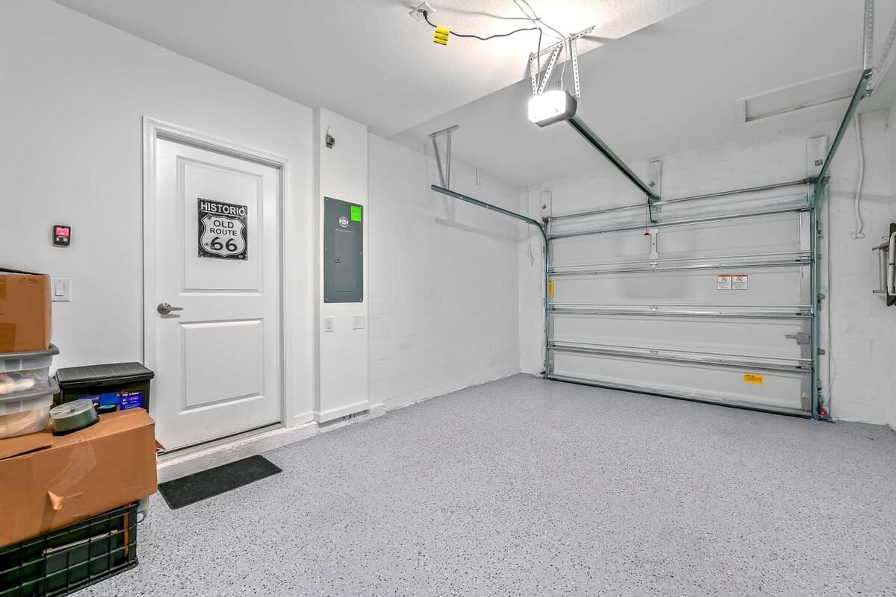 Un garage pulito e vuoto, con una porta bianca, un basculante e un cartello sulla porta.