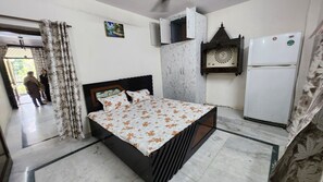 Une chambre à coucher comprenant un lit, une armoire, un réfrigérateur et un élément décoratif mural.