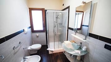 Un baño con cabina de ducha de vidrio, inodoro, lavabo y espejo.