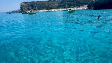 Una vista despejada de un muelle de madera que se adentra en un mar turquesa, con acantilados rocosos al fondo.