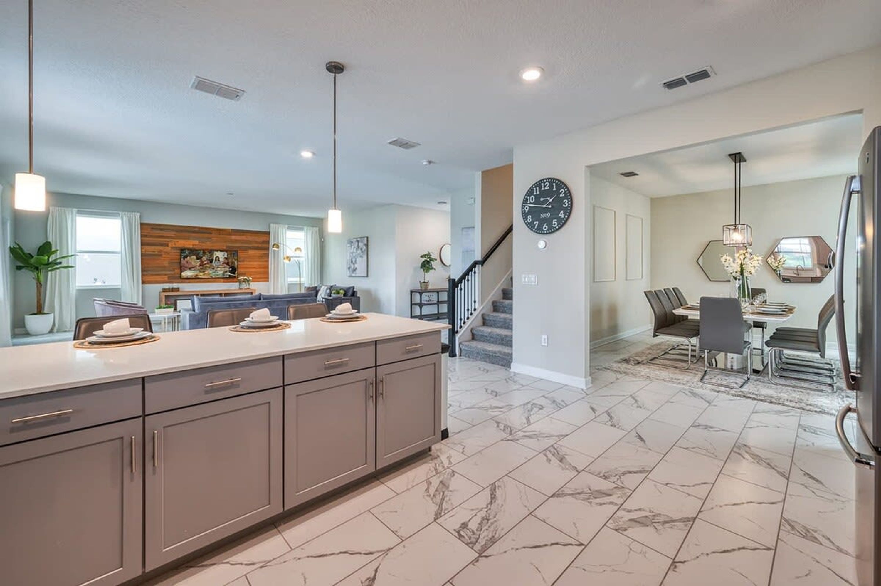 A spacious kitchen with a marble floor, a large island, and modern cabinetry.