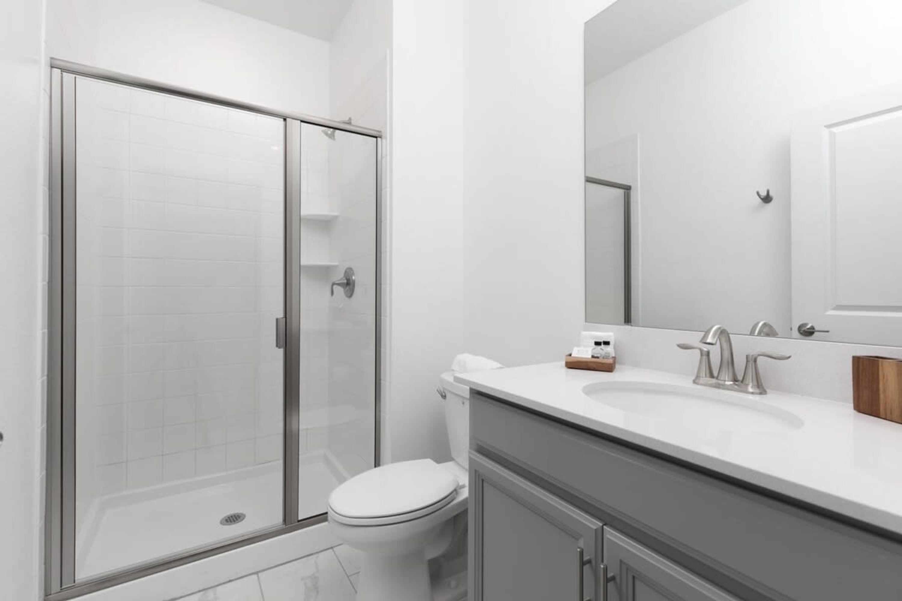 A modern bathroom with a glass shower enclosure, a white toilet, and a vanity with a mirror.