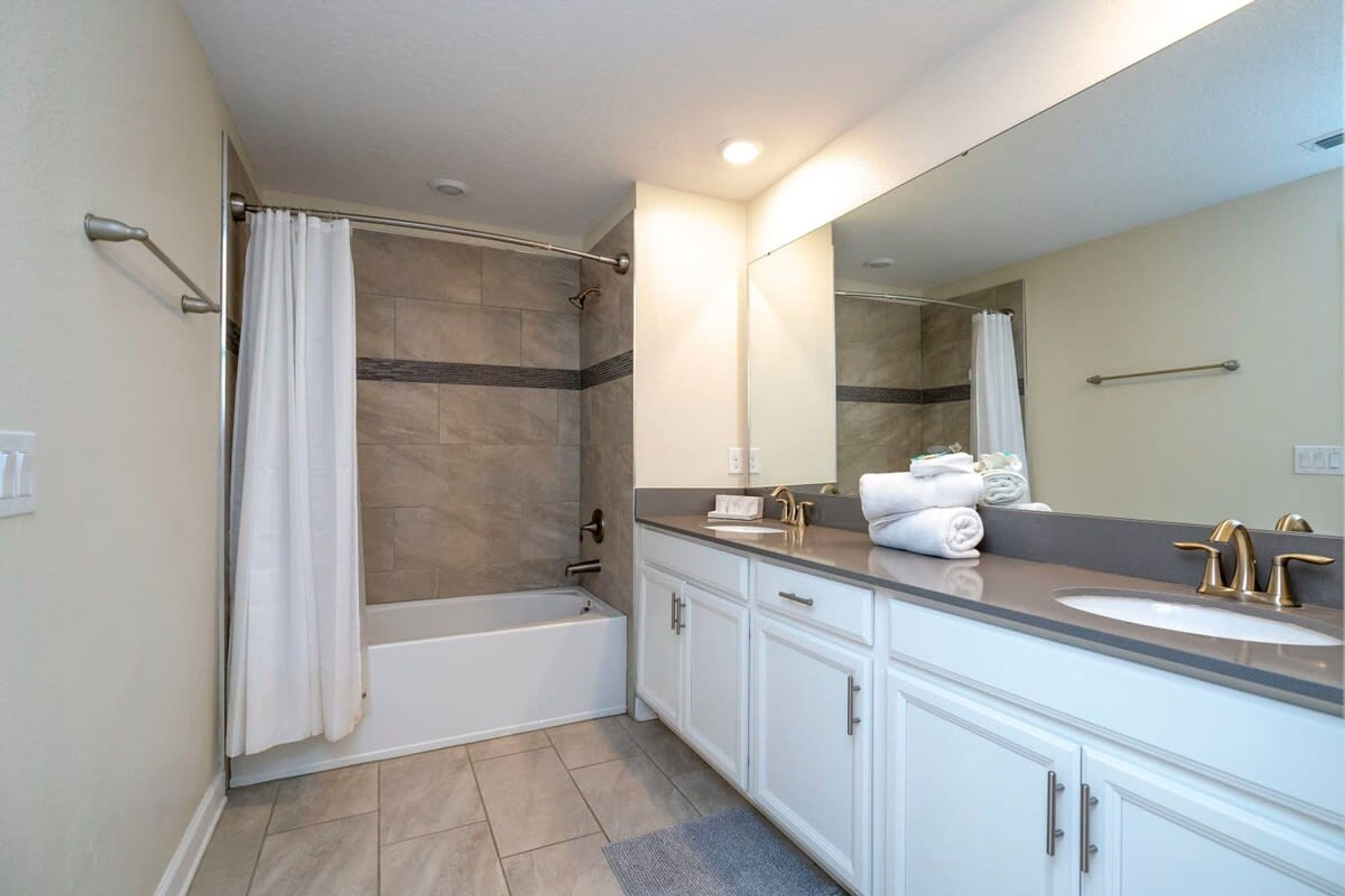 A modern bathroom with a bathtub, a sink, and a large mirror.