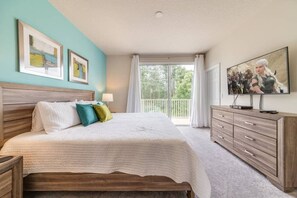 Ein Schlafzimmer mit Bett, Kommode, Fernseher und Balkon.