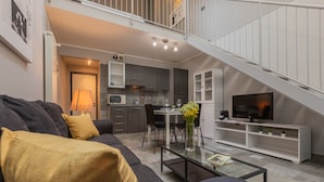 A modern living room with a sofa, coffee table, and a TV. There is a staircase leading to an upper level. - Loft Stampa by Wonderful Italy (Turin)