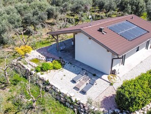 A house with a solar panel roof, a covered patio, and a stone pathway leading to the entrance. - In einem spektakulären Olivenhain in einer ruhig by Interhome (Bardolino)