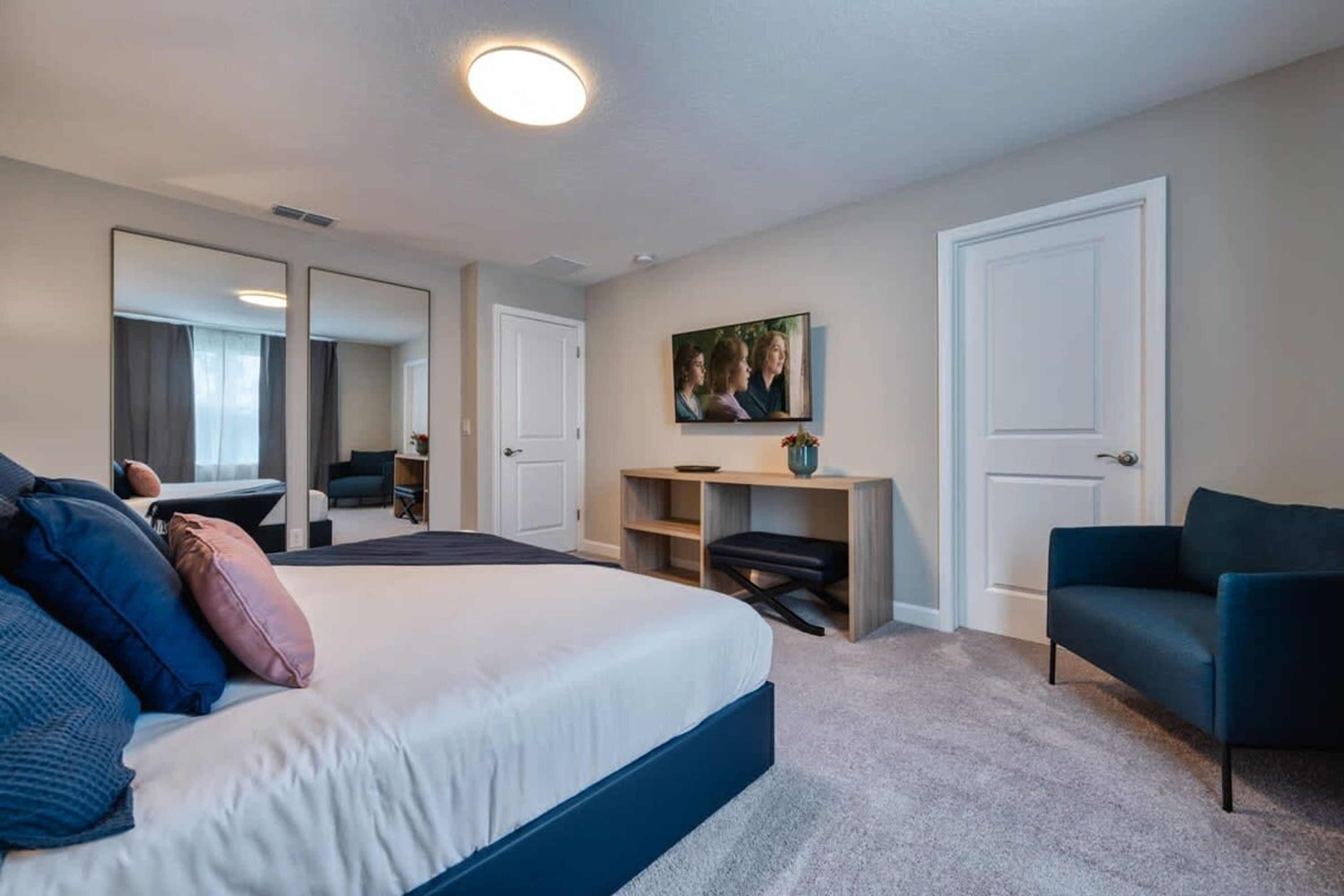 Ett hotellrum med en stor säng, ett skrivbord, en stol och en tv på väggen.