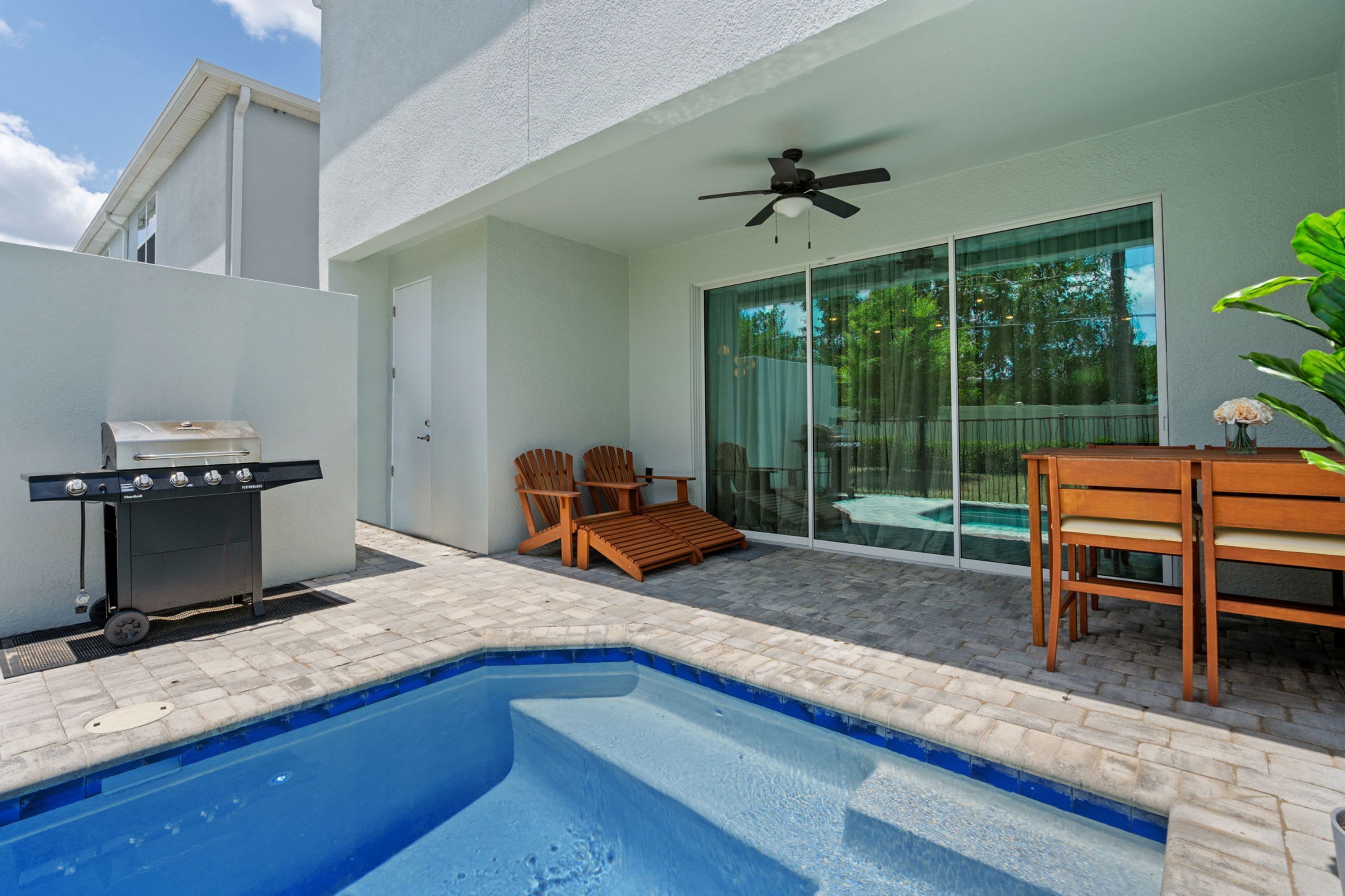 Ein Swimmingpool mit Grill, Holzbänken und einem Tisch.