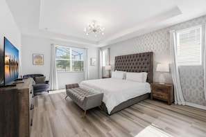 Ein modernes Schlafzimmer mit einem großen Bett, einer Sitzecke und einem Fernseher.